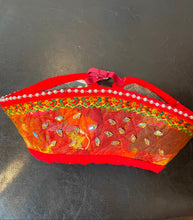 Load image into Gallery viewer, Decorative red headdress with floral patterns on a black surface