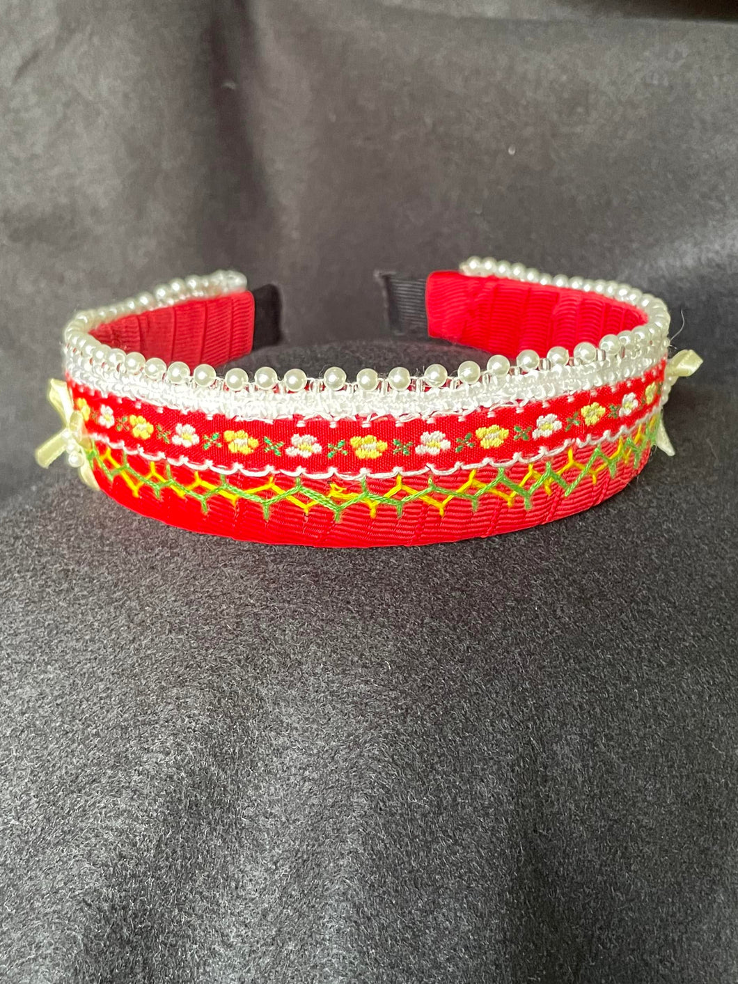 Red and gold embroidered hair clip on a dark fabric background