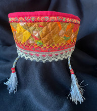 Load image into Gallery viewer, Decorative fabric head piece with intricate patterns and tassels on a dark background